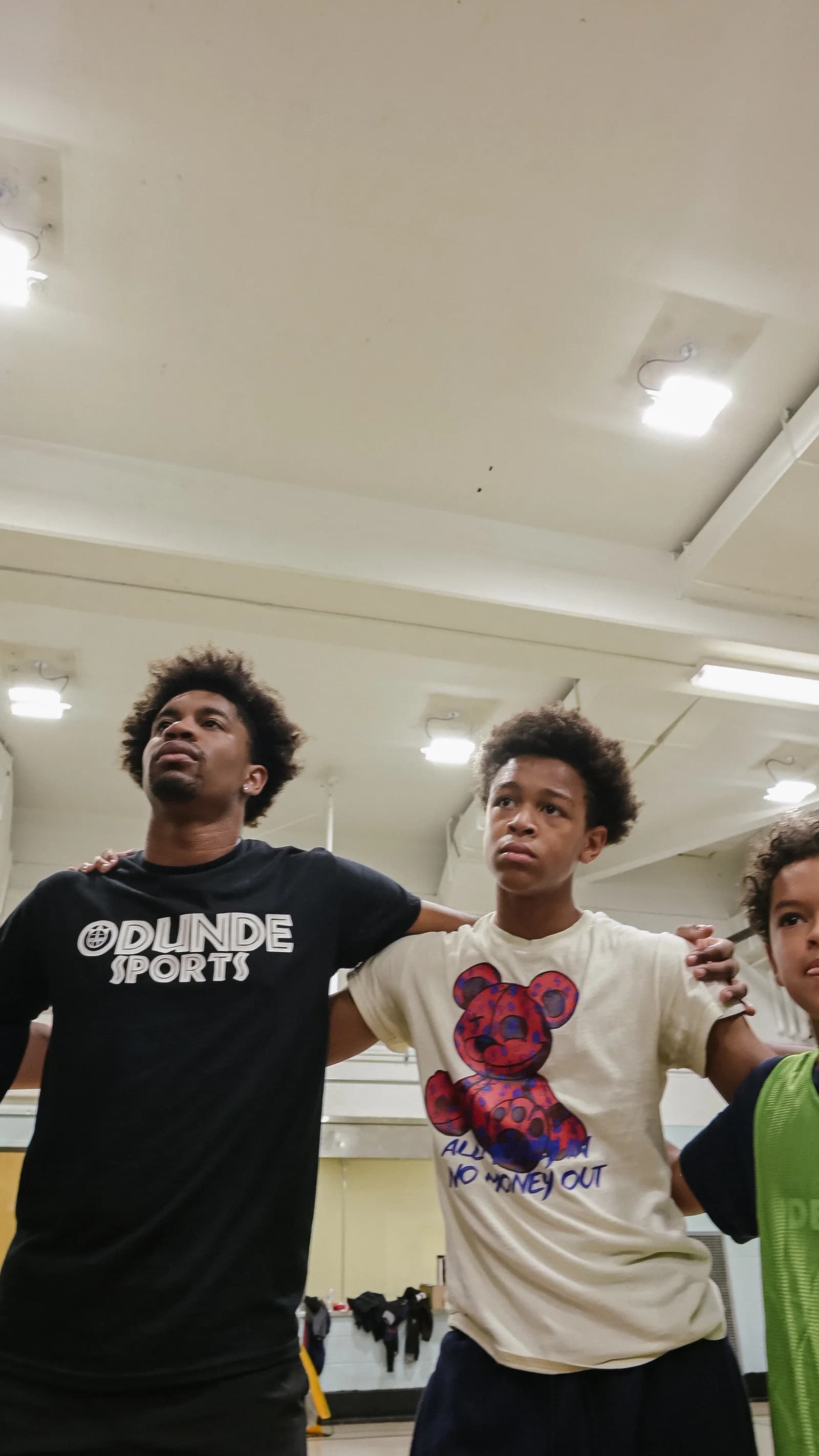 Coach and young athletes with arms linked showing team unity