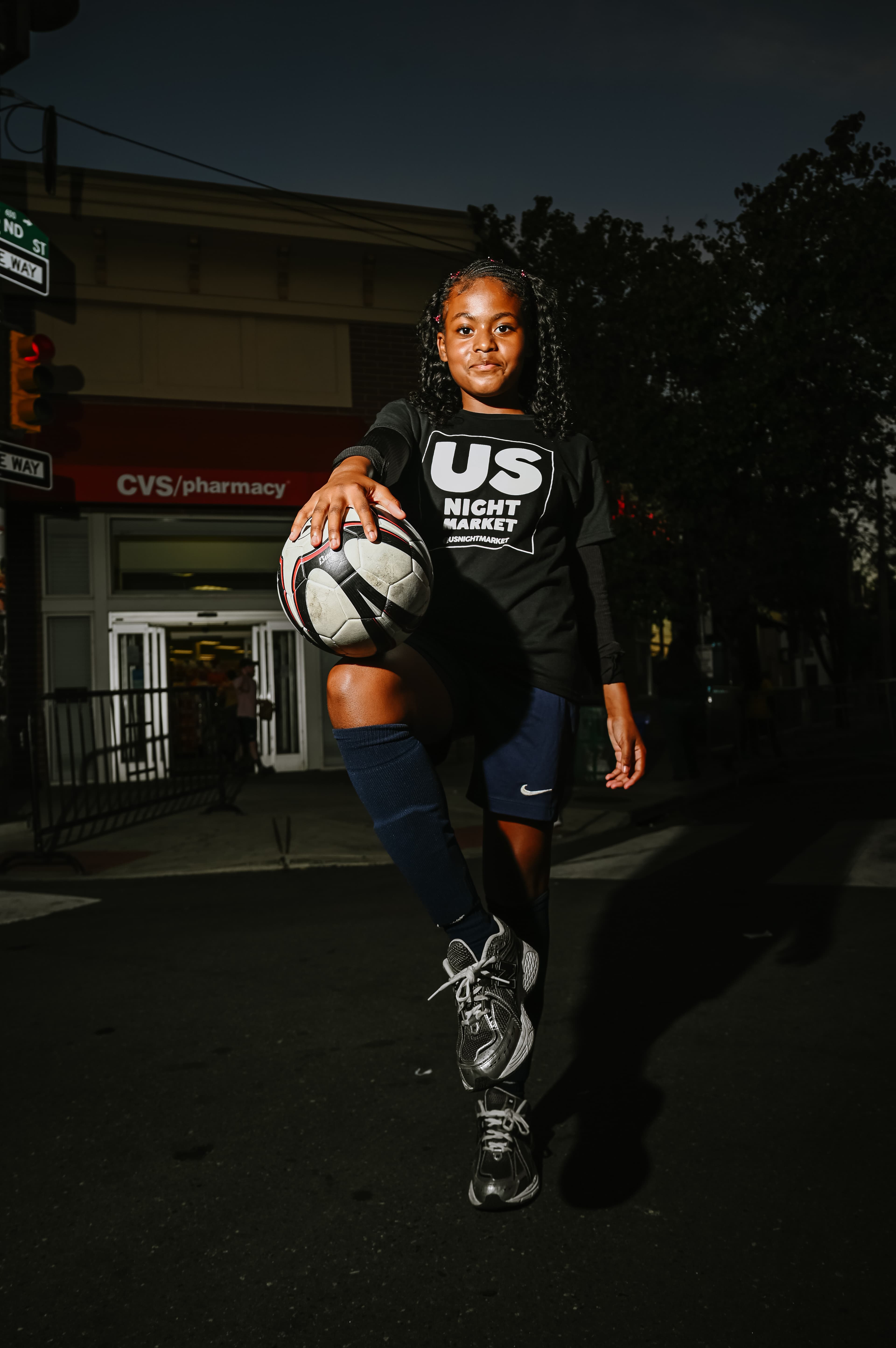 Young athlete confidently presenting a soccer ball at night
